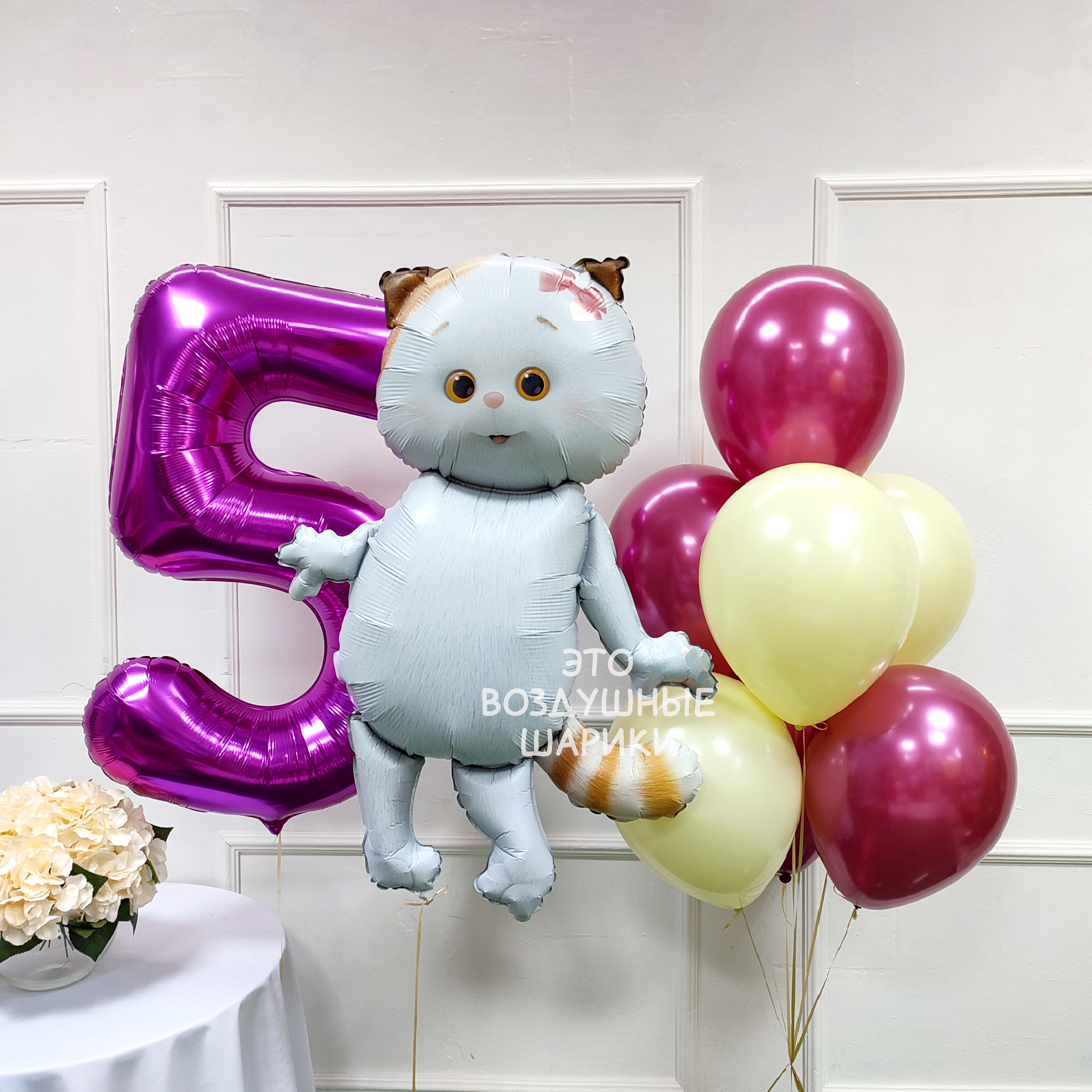 Праздничный набор шаров на 5 лет для девочки с фигуркой кошечки Лилу и ростовой цифрой 5. Крупный план фольгированной фигурки кошечки Лилу на подставке. Ростовая цифра 5 из фольги высотой 102 см в центре композиции. Четыре гелиевых хром-шара и три матовых латексных шара в розово-золотой гамме. Грузы ручной работы и транспортные пакеты для набора шаров.